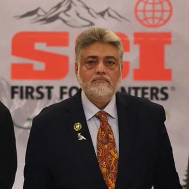 Syed Sumsam Ali Bukhari, Chairman of the chapter, in a navy blazer and patterned tie in front of the SCI backdrop.