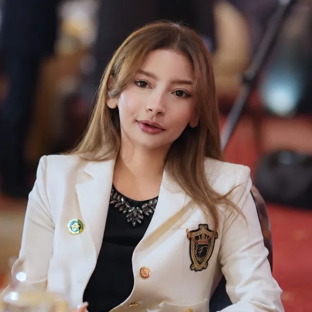 Dania Awan, Director Strategy and Development, in a white blazer with a chapter crest, seated at a gala table.