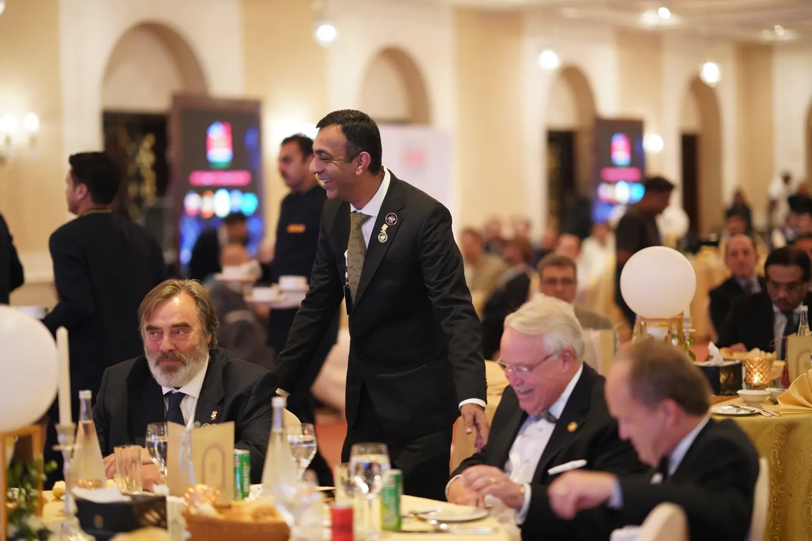 Guests talk across the gala tables in the ballroom.