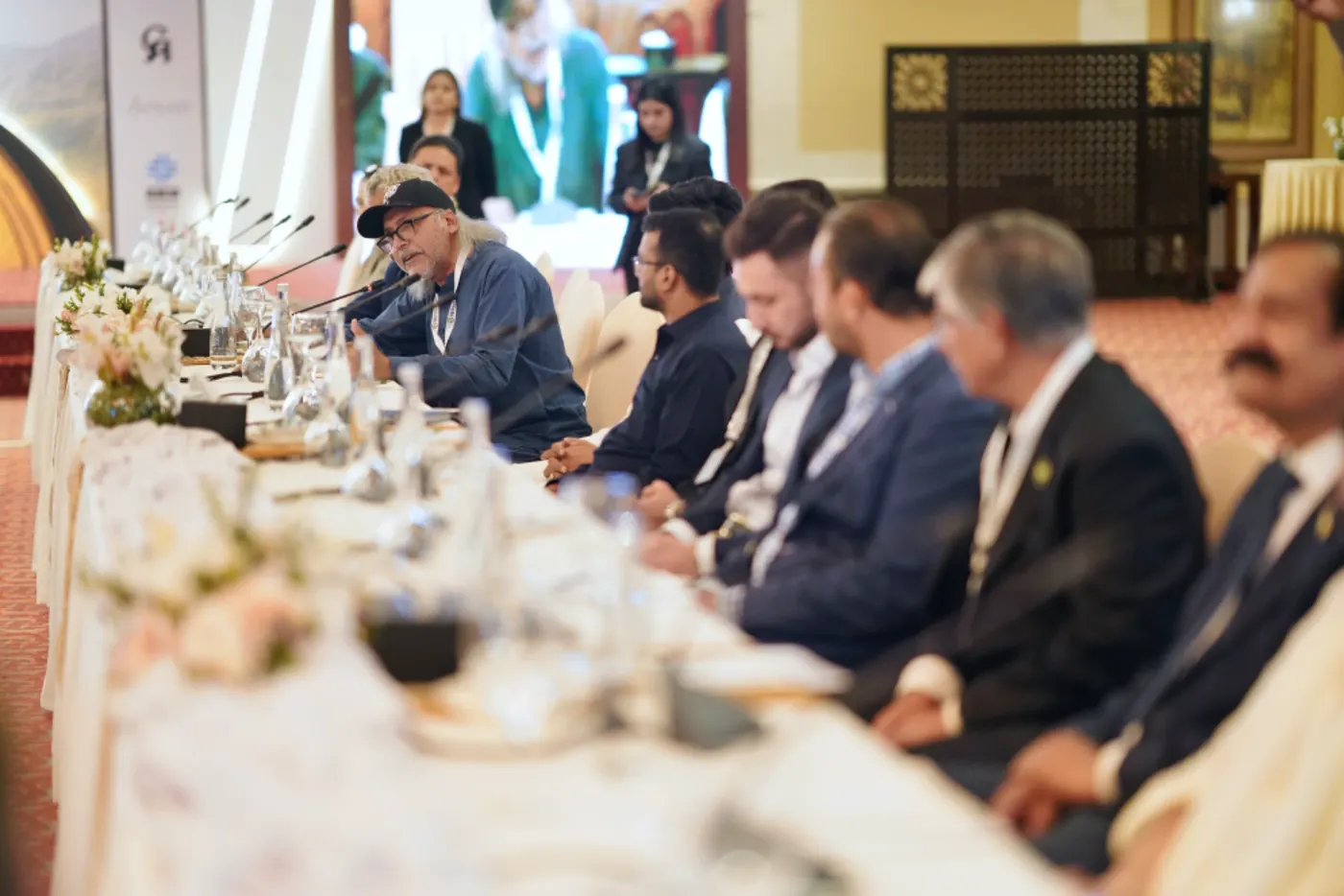 Delegates listen along the length of the conference table as a speaker addresses them.