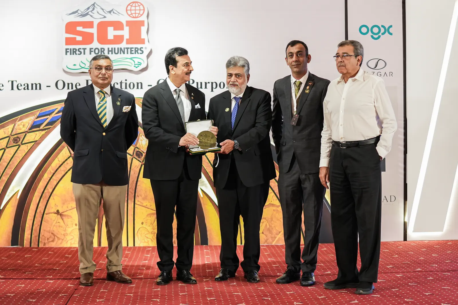 Chapter members present an award on stage in front of the SCI banner.