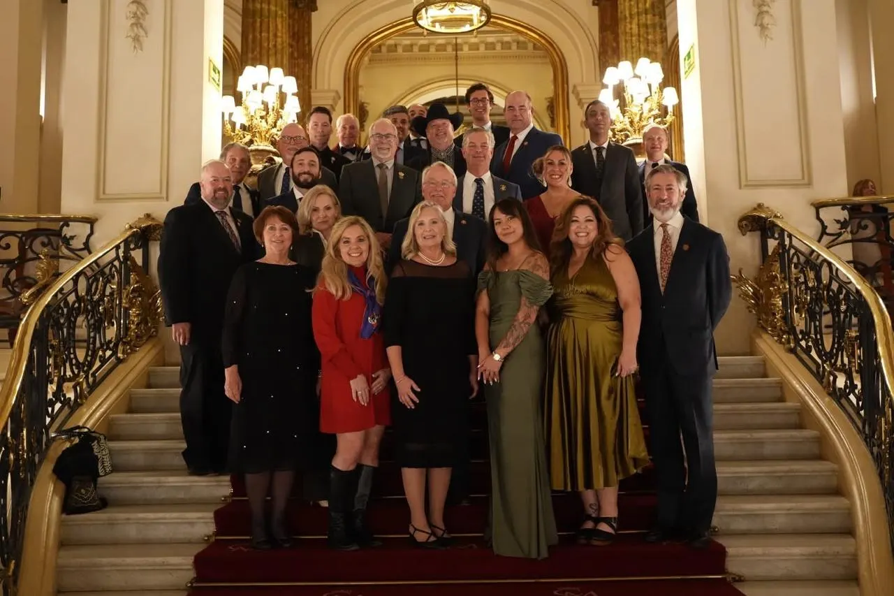 Members of several SCI chapters pose together on a grand staircase.