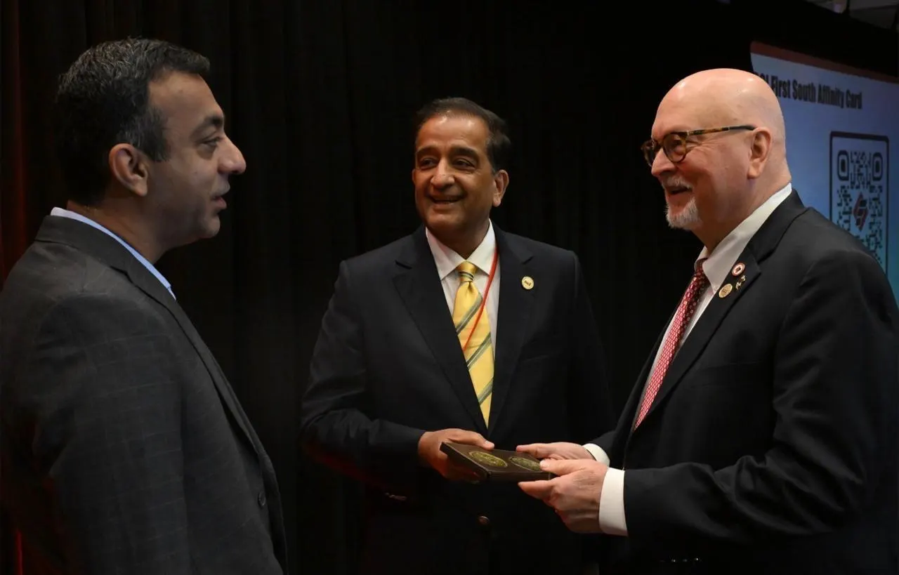 A chapter representative presents a gift to a senior SCI official as a colleague looks on, in Washington, DC.